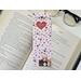 this kitty bookmark has red and pink hearts, paw prints and a light pink  background with four cute cats in the bottom right.