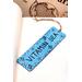 Front of bookmark, light blue background, black handwritten lettering, turtles, starfish, jute rope tassel.