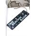 Front of bookmark, black background, handwritten lettering in white, starfish, turtles, jute rope tassel.