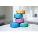 Stack of NMJ shampoo bars in gold, teal, pink, and blue, perfect for eco-conscious hair care.