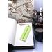 Front of bookmark, lime green background, handwritten black lettering, white and black dot art flowers, jute rope tassel.
