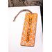 Front of bookmark, orange background, handwritten black lettering, white and black dot art flowers, jute rope tassel.