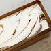Close up of tea caddy with gold and black ribbons on white background.