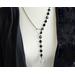 Asymmetrical lariat necklace: one side black coin beads, silver spacers, pewter dangle, other side rhodium chain connected by pewter loop