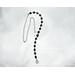 Asymmetrical lariat necklace: one side black coin beads, silver spacers, pewter dangle, other side rhodium chain connected by pewter loop