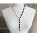 Asymmetrical lariat necklace: one side black coin beads, silver spacers, pewter dangle, other side rhodium chain connected by pewter loop