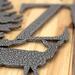 Close up of silver vein powder coat on our custom family name metal sign with doe deer silhouette.