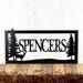 Rectangular metal family name sign, with a doe deer silhouette, in matte black powder coat.