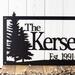 Close up of pine trees on our family last name and established year metal sign, in matte black powder coat.