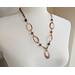 Handcrafted copper necklace with hammered washers, faceted petrified wood beads, and a 1" pendant, featuring a rustic boho design.