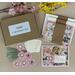 Card making kit with gold foil floral patterned scrapbook paper, pink cardstock, pink flowers, green ribbons and off-white Bloom sentiments.