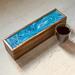 Beautiful mango wood tea box with 5-compartments.  Top finished in shades of light blue and white with a durable glossy resin finish.