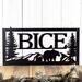 Close up of rectangular metal family name plaque with bear and mountains, in matte black powder coat.