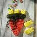 Medium dark orange crochet carrot pouch with dark green top with 3 peep marshmallow bunnies poking out of the top to show width.