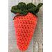 Medium dark orange crochet carrot pouch with dark green top  filled to show round shape once filled. Tie can be tightened and secured.