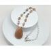 Handcrafted necklace with a peach moonstone pendant and sun hematoid beads on a stainless steel chain, 23" long with a 2" pendant.