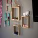 A closeup side-angle of a modern square shelf, handcrafted wood in a natural color. A stylish way to display a collection of 3-D Dragons.
