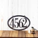 Horizontal oval 4 digit metal house number sign, in raw steel.