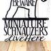 Close up of Miniature Schnauzers Live Here metal sign, with Beware, in matte black powder coat.
