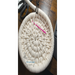 A handcrafted round basket in progress with a crochet hook and scissors nearby, resting on a wooden table with part of a keyboard visible.