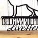 Close up of Belgian Shepherds Live Here metal wall decor, in matte black powder coat.