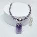 A handcrafted amethyst beaded necklace with a wire-wrapped pendant, silver-toned accents, and a steel chain, displayed on a white background