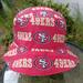 Front top view of bucket hat on stand. Fabric has red and gold SF 49ers logos on red background