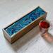 Organize your tea bags and enjoy this functional art in your home and kitchen. Deep, rich teal and gold ribbons.