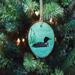 A hand-painted common loon wood slice Christmas ornament hanging on a Christmas tree.  The ornament is available at Cove Creek Photography.