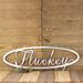 Oval family last name metal sign with script font, in raw steel.