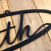 Close up of matte black powder coat on our metal oval family sign with script font.