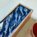 Dark blue with waves of white and silver on top of tea organizing box.