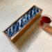 Bold ocean wave pattern on top of this wooden tea caddy that holds 50 tea bags.