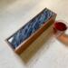 A dark blue background  with ribbons of white an d silver give the impression of movement on top of this wooden tea box.  Perfect for Father's Day or a wedding gift for the tea lover.