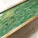 Close up of the green and gold design on top of this tea caddy large enough to sort up to 50 tea bags.