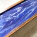 A close up of the design created with quality acrylics and glossy resin.  Shades of purple swirl together with white on the cover of this 5-compartment tea chest.