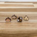 Picture of four wooden stud earrings; a gold crown with a pink heart, and one with a purple heart, a honey bee, and a honeycomb.