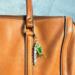 Green fish charm with personalized name hanging from a purse.