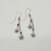 Handmade 2.5 inch dangle earrings with violet swirl crystal beads and silver daisy flower charms on delicate chains.