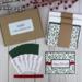 A handmade Happy Holiday card kit with holly scrapbook paper, cardstock, stamped sentiment, ribbon and envelope to DIY 6 Christmas cards.