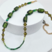 An 18-inch handmade necklace with vintage olive-green glass beads, bicones, and seed beads on a gold-plated stainless steel chain