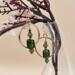 A pair of handmade 2-inch earrings with olive green vintage glass beads, green glass bicones and gold spacers with gold-plated circle frame