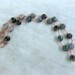 Moss agate beads in shades of teal, green and blue are linked by wire wrapping to form a necklace with copper clasp. 