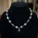 Moss agate beads in shades of teal, green and blue are linked by wire wrapping to form a necklace with copper clasp. 