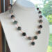 Moss agate beads in shades of teal, green and blue are linked by wire wrapping to form a necklace with copper clasp. 