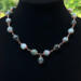 Moss agate beads in shades of teal, green and blue are linked by wire wrapping to form a necklace with copper clasp. 