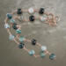 Moss agate beads in shades of teal, green and blue are linked by wire wrapping to form a necklace with copper clasp. 