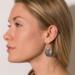  Side view of a person wearing a sterling silver hammered pear dangle earring, showcasing the design and ear wire.

