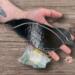 Crow stained glass suncatcher by Robin C. Hary being held for size reference- h: 7" x w: 5".