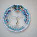 silver yarn wrapped metal hoop cradles wire tree of life. Several color seed beads adorn the branches and roots. Hematite star centers top